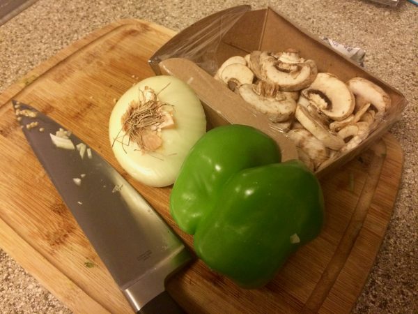 Cutting board with bell peppers, onions, and mushrooms.